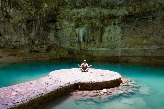 Cenote Suytún seen from above, one person sitting alone on the stone platform