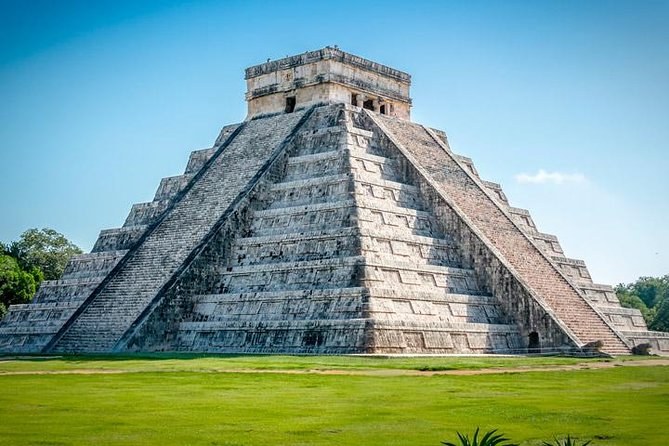 El Castillo, the stepped pyramid at Chichen Itza, on open grass under a blue sky
