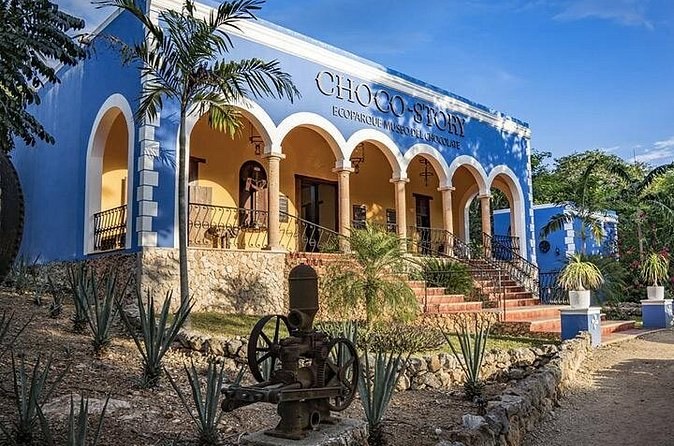 The blue arcaded building of the Choco-Story museum opposite Uxmal, with agaves planted in front