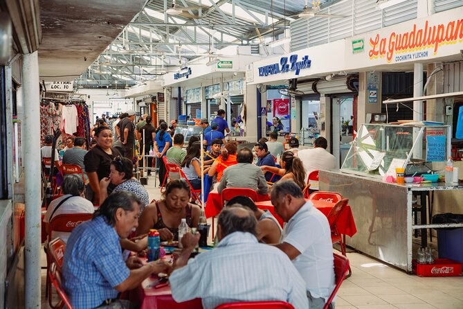 An aisle of lunch counters inside a Merida market with diners at the tables