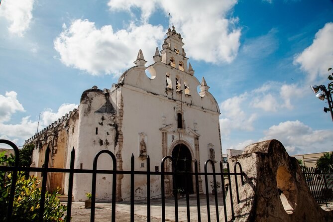A whitewashed colonial church in one of Merida's barrios under a blue sky